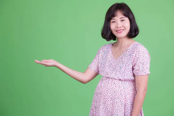 Retrato de feliz mulher grávida asiática mostrando algo — Fotografia de Stock