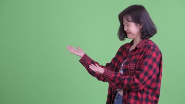 Счастливая азиатская женщина-хипстер что-то показывает — стоковое видео