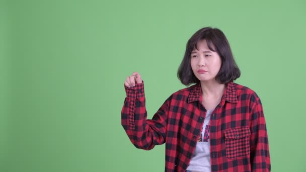Stressad asiatisk hipster kvinna tänker medan pekar upp — Stockvideo