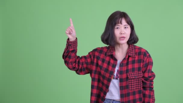 Feliz asiático hipster mujer hablando mientras apuntando hacia arriba — Vídeo de stock