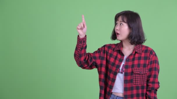 Gelukkig aziatische hipster vrouw wijzend omhoog en kijken verrast — Stockvideo