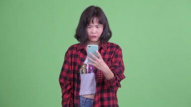 Stresli Asyalı hippi kadın telefonu kullanıyor ve kötü haberler alıyor.