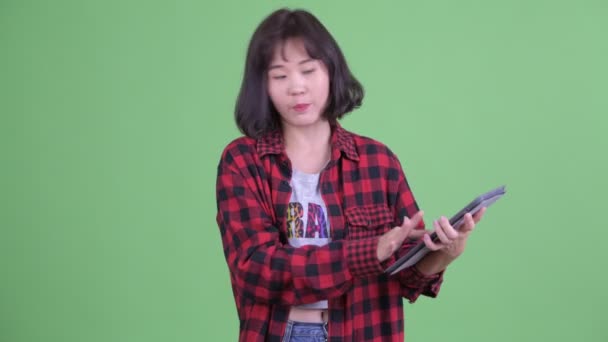 幸せなアジアのヒップスター女性は、デジタルタブレットを使用している間話す — ストック動画