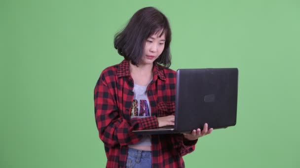 Glücklich asiatische hipster Frau denken, während mit laptop — Stockvideo