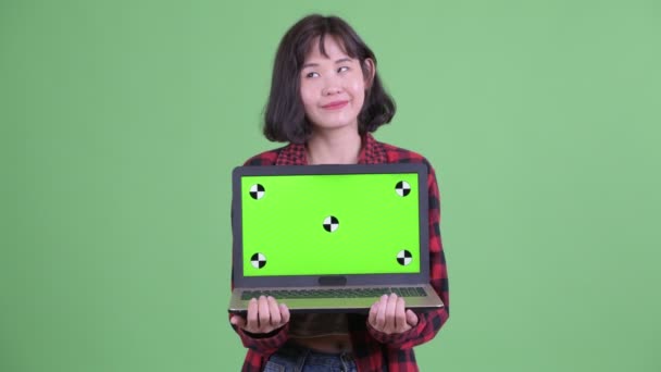 Щаслива азіатська гіпстерка думає, коли показує ноутбук. — стокове відео