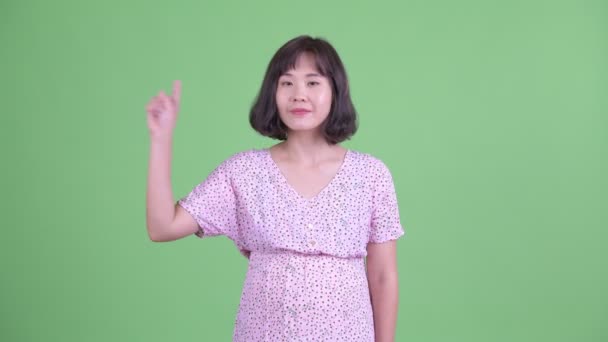 Happy Asian pregnant woman pointing up — Stock Video