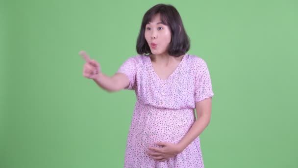 Happy Asian pregnant woman pointing finger — Stock Video