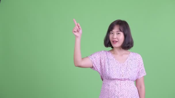 Happy Asian pregnant woman thinking while pointing up — Stock Video