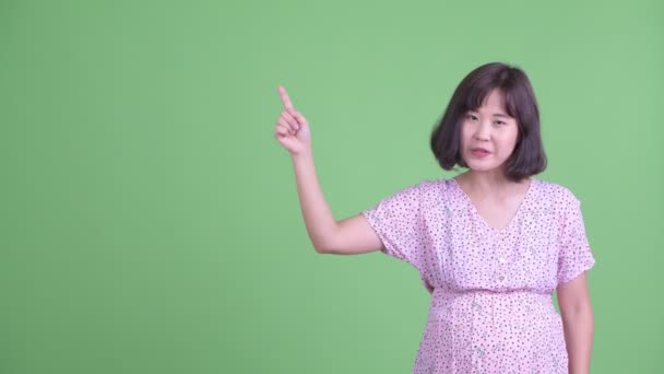 Happy Asian pregnant woman talking while pointing up — Stock Video