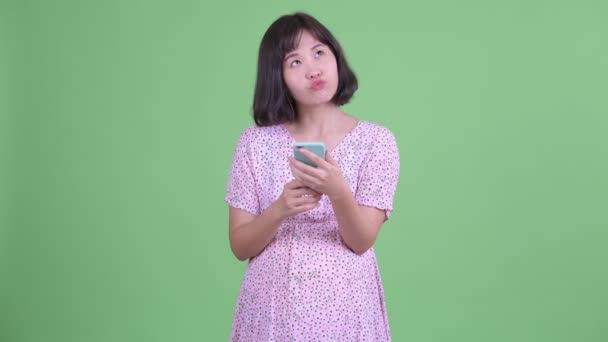 Heureuse asiatique femme enceinte penser tout en utilisant téléphone — Video