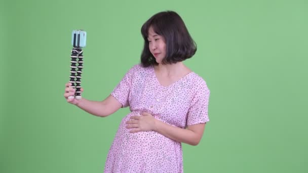 Ευτυχισμένη ασιατική έγκυος γυναίκα vlogging με τηλέφωνο — Αρχείο Βίντεο