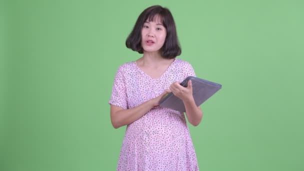 Heureuse asiatique enceinte femme parler tout en utilisant numérique tablette — Video