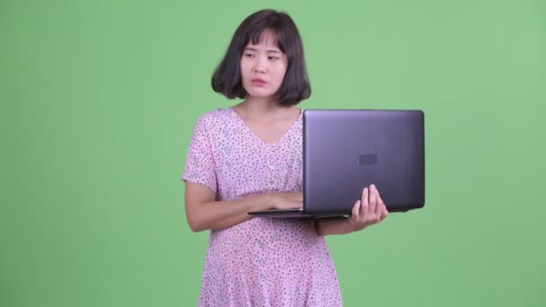 Feliz asiático grávida mulher pensando ao usar laptop — Vídeo de Stock