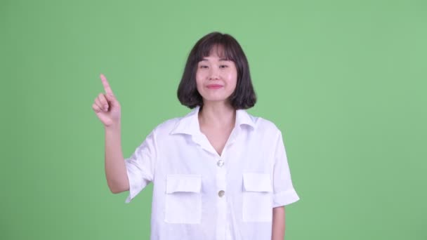 Glücklich schön asiatische Geschäftsfrau zeigt nach oben — Stockvideo
