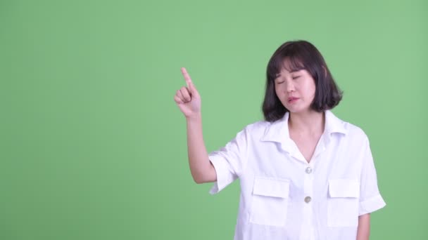 Stressed Asian businesswoman talking while pointing up — Stock Video