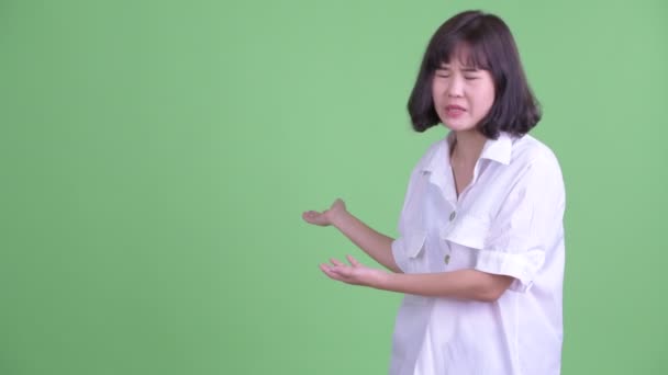 Стрессовая азиатская деловая женщина разговаривает, показывая спине — стоковое видео