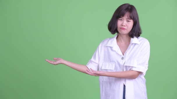 Стрессовая азиатская деловая женщина говорит, показывая что-то — стоковое видео