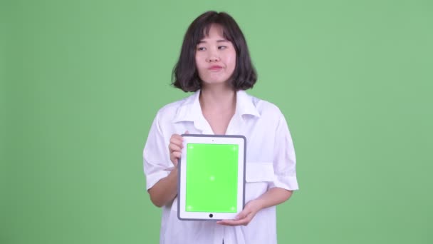 Щасливі красиві азіатські бізнес-леді думаючи, показуючи, що цифровий планшетний — стокове відео