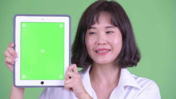 Visage de heureux asiatique femme d'affaires parler tout en montrant tablette numérique — Video