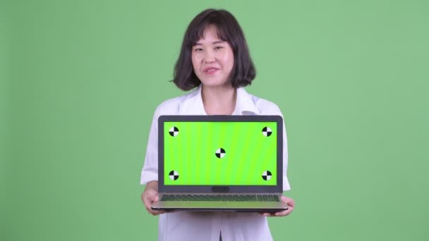 Happy beautiful Asian businesswoman talking while showing laptop — Stock Video