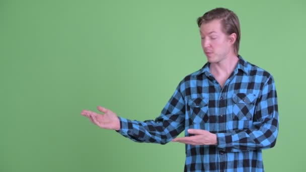 Boldog ifjú csinos csípő ember beszél, miközben mutat valamit — Stock videók