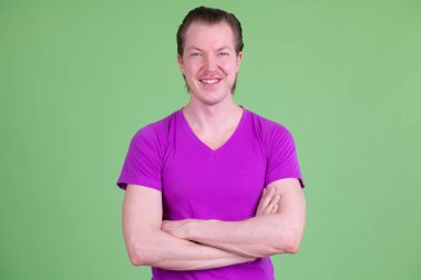 Kollarını kavuşturup gülümseyen mutlu genç adamın portresi.