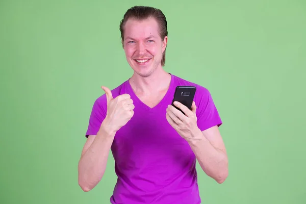 Portrét šťastný mladý muž pomocí telefonu a dávat palce nahoru — Stock fotografie