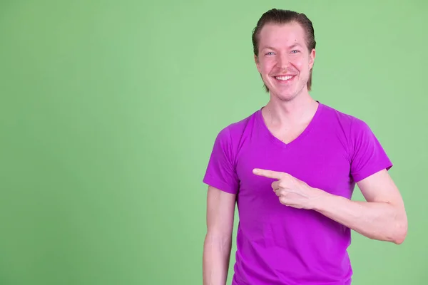 Retrato de jovem e bonito homem feliz apontando para o lado — Fotografia de Stock