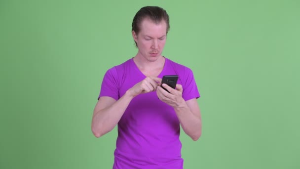 Наголошений молодий чоловік використовує телефон і виглядає сумно — стокове відео