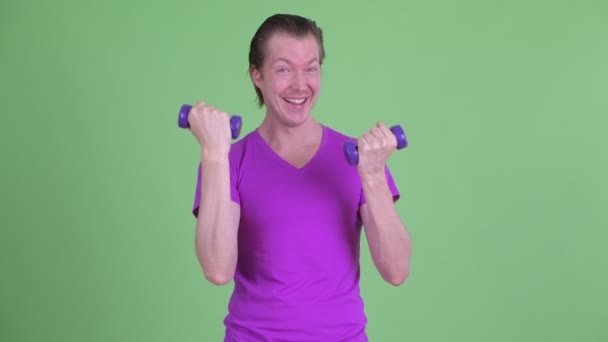 Happy young handsome man exercising with dumbbells — Stock Video