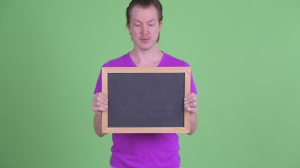 Happy young handsome man holding blackboard — Stock Video
