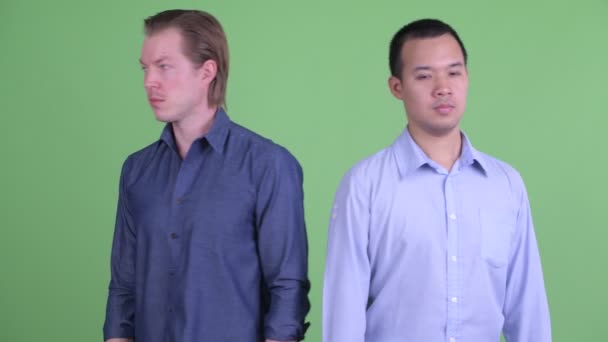 Twee multi-etnische zakenmannen draaien zich om en kijken samen bang — Stockvideo