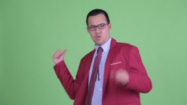 Gözlüklü mutlu Asyalı işadamı başparmağını kaldırıyor ve heyecanlı görünüyor.