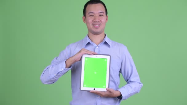 Happy Asian businessman talking while showing digital tablet — Stock Video