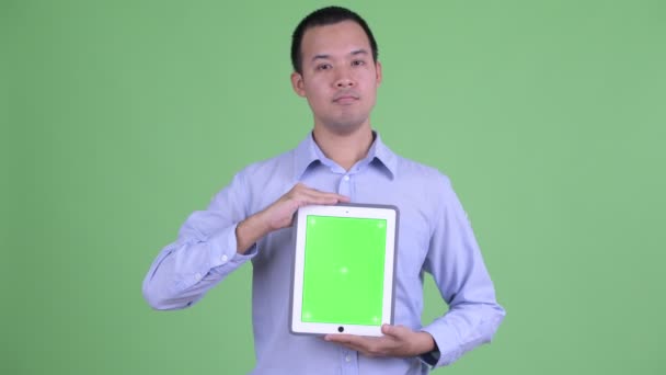 Happy Asian businessman thinking while showing digital tablet — Stock Video