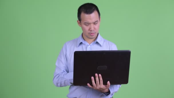 Feliz asiático empresario pensando mientras se utiliza el ordenador portátil — Vídeos de Stock