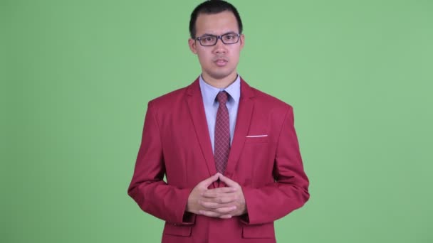 Щасливий азіатський бізнесмен з окулярами, який щось пояснює. — стокове відео