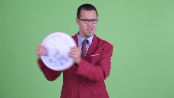 Злой азиатский бизнесмен в очках показывает время — стоковое видео