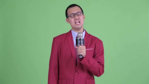 Asijský podnikatel s brýlemi zpěv s mikrofonem — Stock video