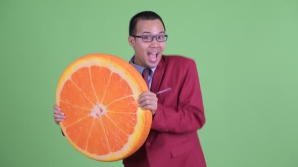 Szczęśliwy azjatycki biznesmen z okularami trzyma pomarańczową poduszkę jako zdrową koncepcję — Wideo stockowe