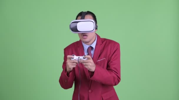 Азиатский бизнесмен в костюме с использованием гарнитуры виртуальной реальности и игр — стоковое видео