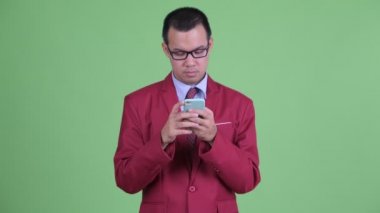 Mutlu Asyalı işadamı telefonu kullanıyor ve şaşırmış görünüyor.