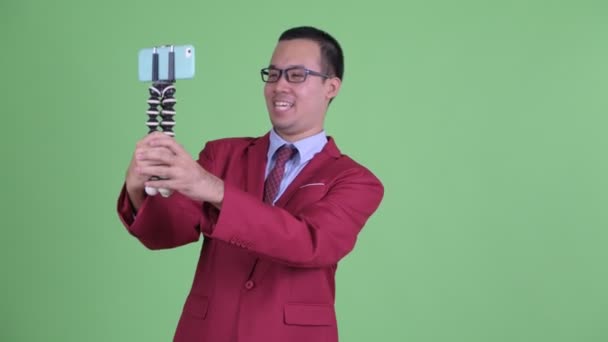 Щасливий азійський бізнесмен, який веде блог по телефону. — стокове відео