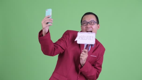 Feliz asiático hombre de negocios tomando selfie con papel signo — Vídeo de stock