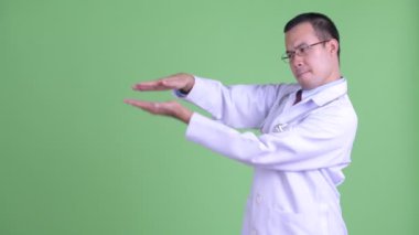 Mutlu Asyalı doktor parmaklarını şaklatıyor ve bir şey gösteriyor.