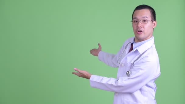 Счастливый азиатский врач говорит, показывая спине — стоковое видео