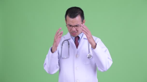 Stressed Asian man doctor with eyeglasses having headache — Stock Video