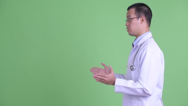 Vue du profil de happy Asian man doctor avec des lunettes parler — Video