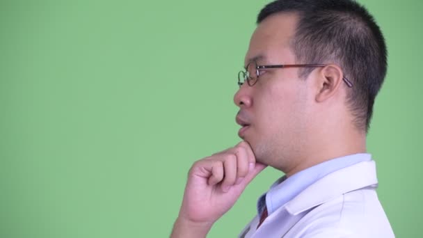 Primer plano perfil vista de feliz asiático hombre médico con gafas pensando — Vídeos de Stock