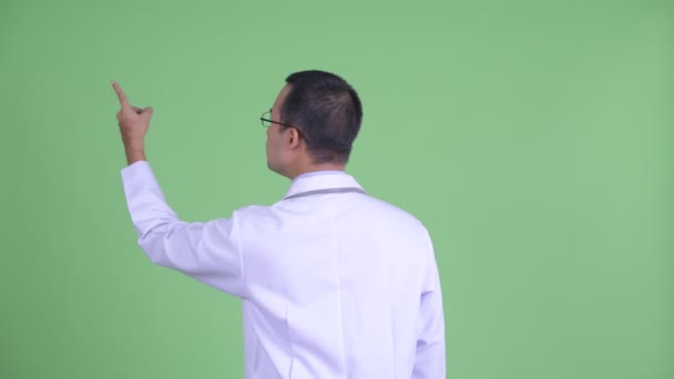 眼鏡を指差し指で指差すアジア人男性医師の背面図 — ストック動画